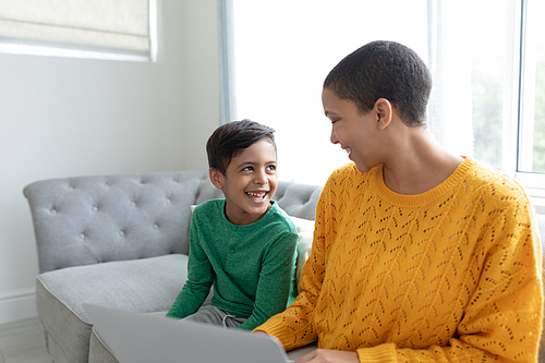Side view of African american mother and son using laptop on a sofa in living room at home