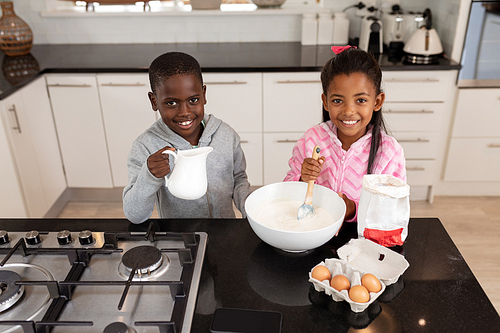 Front view of African american Siblings preparing food on a worktop in kitchen at home