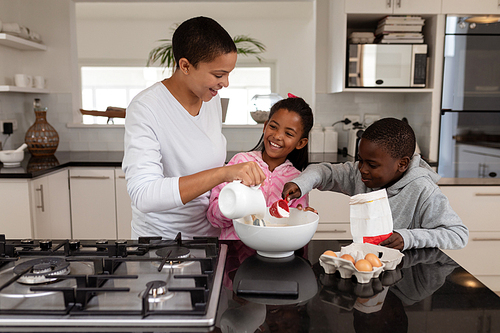 Front view of African american Mother and children preparing food on a worktop in kitchen at home