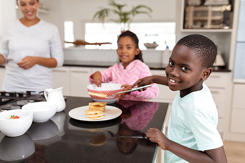 Front view of African american Mother and children preparing food on a worktop in kitchen at home