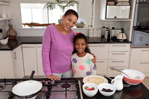 Front view of African american Mother and daughter standing together in kitchen at home