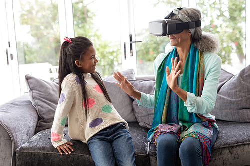 Front view of African american Grandmother with granddaughter using virtual reality headset in living room at home