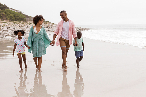 Front view of Happy African american family walking together hand in hand on the beach