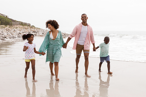Front view of Happy African american family walking together hand in hand on the beach