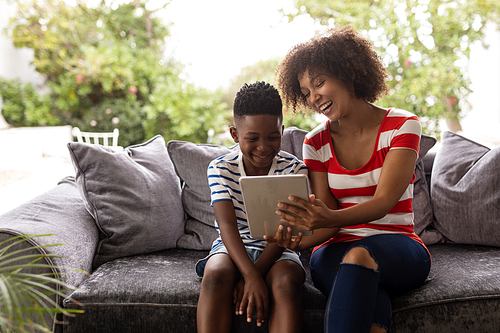 Front view of African american Mother and son using digital tablet on a sofa in living room at home