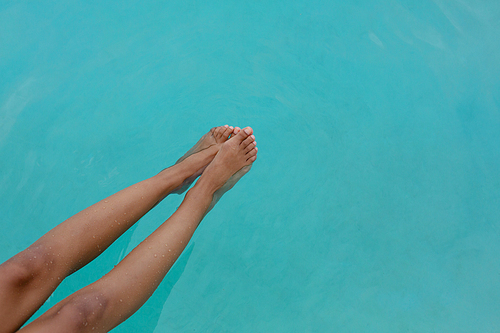 Low section of Caucasian woman's feet in swimming pool. Summer fun at home by the swimming pool