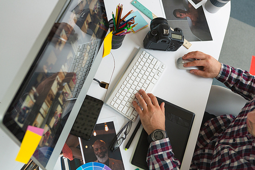 Mid section close-up of handsome young Caucasian male graphic designer working on computer at desk in office. Modern casual creative business concept