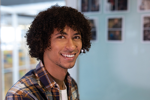 Portrait of mixed-race male graphic designer smiling in office. This is a casual creative start-up business office for a diverse team