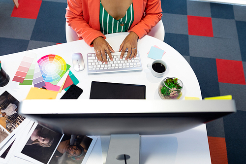 Mid section of young pretty Asian female graphic designer working on computer at desk in office. This is a casual creative start-up business office for a diverse team