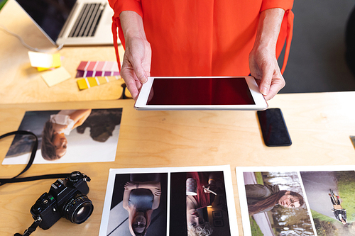 Mid section of Caucasian female graphic designers using digital tablet at desk in office. This is a casual creative start-up business office for a diverse team