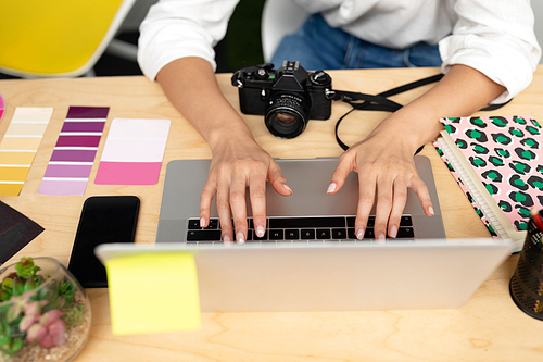 Mid section close-up of Caucasian female graphic designer using laptop at desk in office. This is a casual creative start-up business office for a diverse team