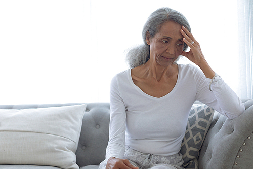 Front view of senior mixed race woman sitting on couch at home. Authentic Senior Retired Life Concept