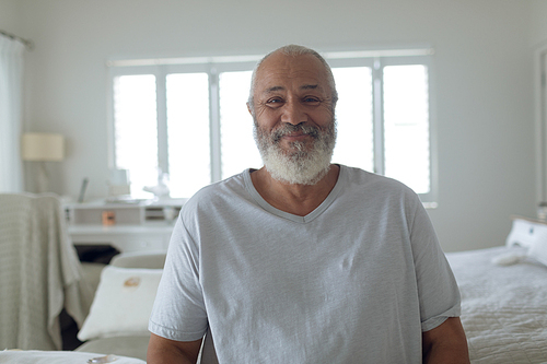 Front view of senior Caucasian man smiling in white bedroom. Authentic Senior Retired Life Concept