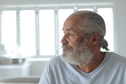 Close up of thoughtful senior Caucasian man sitting on the bed in bedroom. Authentic Senior Retired Life Concept