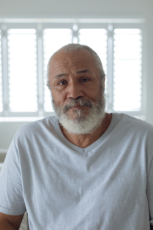 Portrait of thoughtful senior Caucasian man sitting on the bed in bedroom. Authentic Senior Retired Life Concept