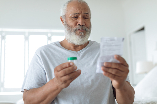 Side view of senior Caucasian man sitting on the bed while reading through the prescription. Authentic Senior Retired Life Concept