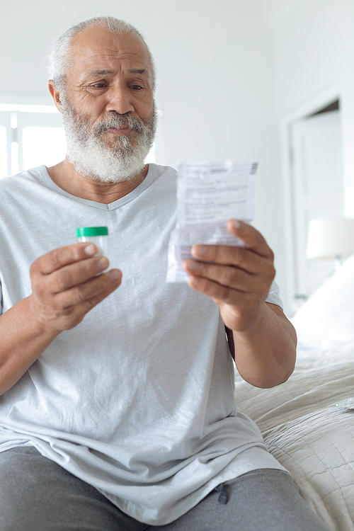 Side view of senior Caucasian man sitting on the bed while reading through the prescription. Authentic Senior Retired Life Concept