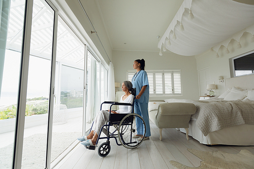 Side view of healthcare worker and woman on a wheelchair indoor. Authentic Senior Retired Life Concept