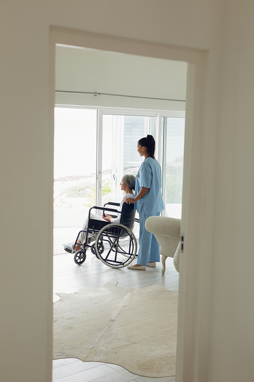 Side view of healthcare worker and woman on wheelchair indoor. Authentic Senior Retired Life Concept