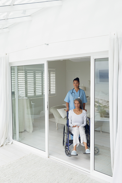 Front view of healthcare worker and woman on a wheelchair indoor. Authentic Senior Retired Life Concept