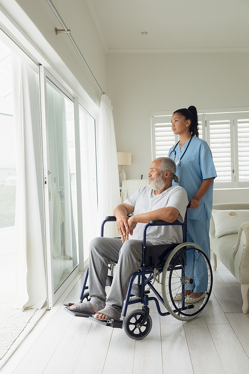 Side view of healthcare worker and man on wheelchair indoor. Authentic Senior Retired Life Concept