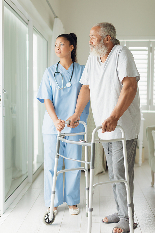 Side view of healthcare worker with man using walking support indoor. Authentic Senior Retired Life Concept