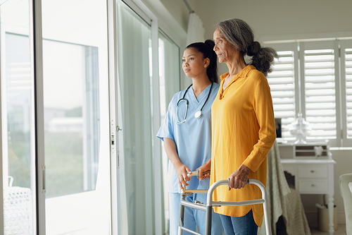 Side view of healthcare worker and woman using walking aid indoor. Authentic Senior Retired Life Concept