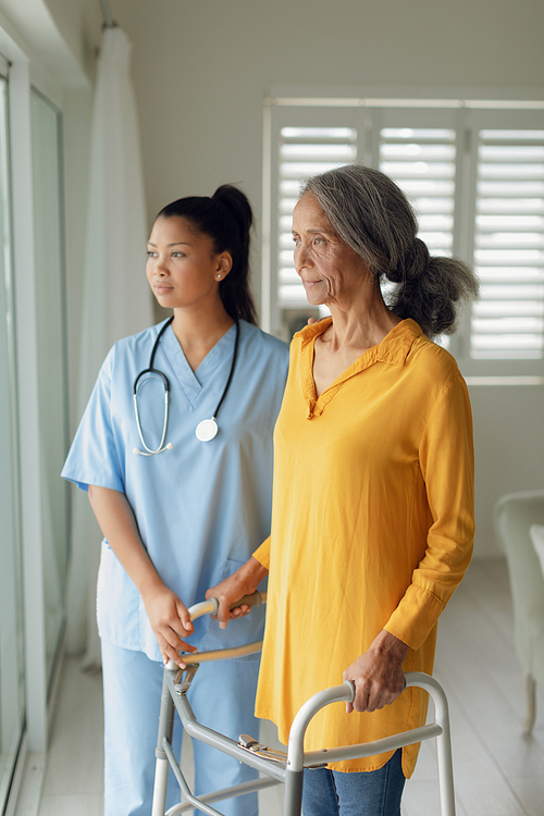 Side view of healthcare worker and a woman using a walking aid indoor. Authentic Senior Retired Life Concept