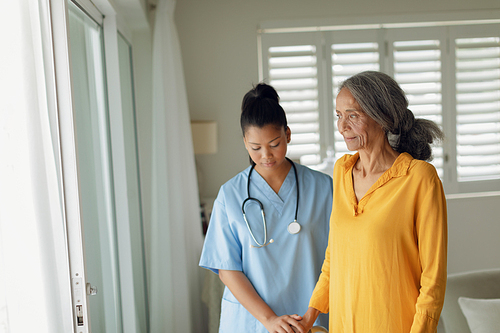 Side view of healthcare mixed-race nurse and Caucasian old woman indoor. Authentic Senior Retired Life Concept