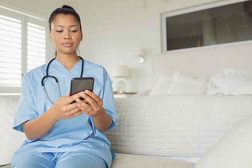 Front view of mixed-race healthcare worker using smartphone indoor. Authentic Senior Retired Life Concept