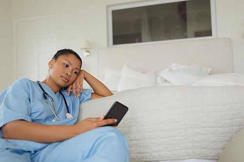 Front view of mixed-race healthcare worker using smartphone indoor. Authentic Senior Retired Life Concept