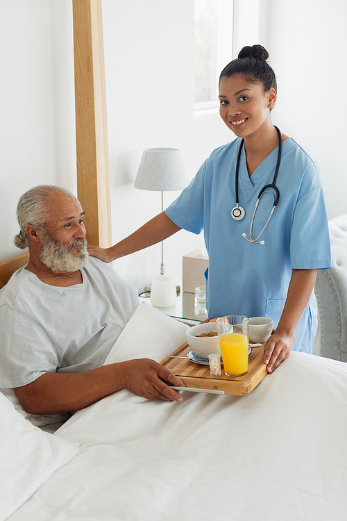 Side view of mixed race healthcare worker talking old man in bed. Authentic Senior Retired Life Concept