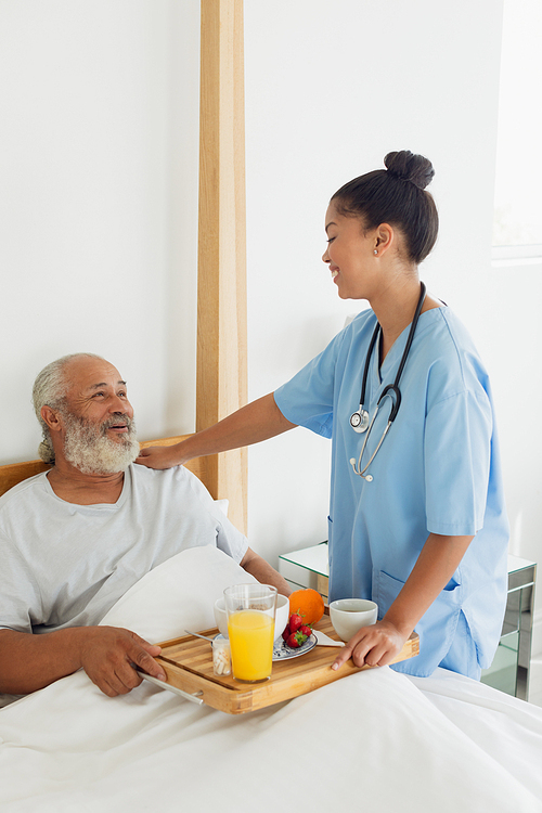 Side view of mixed race healthcare worker talking with old man in bed. Authentic Senior Retired Life Concept