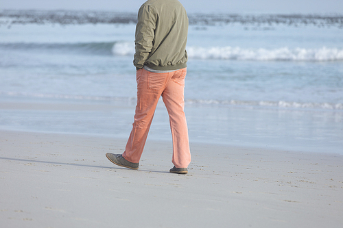 Low section of senior African-American man walking on beach on beautiful day. Authentic Senior Retired Life Concept