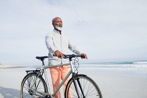Front view of senior African-American walking with bicycle on beach on beautiful day. Authentic Senior Retired Life Concept