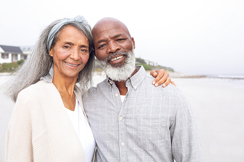 Front view of happy senior African-American couple standing on the beach on cloudy day. Authentic Senior Retired Life Concept