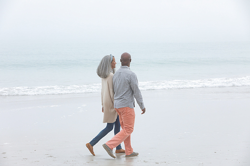 Side view of happy senior African-American couple walking hand in hand on beach. Authentic Senior Retired Life Concept