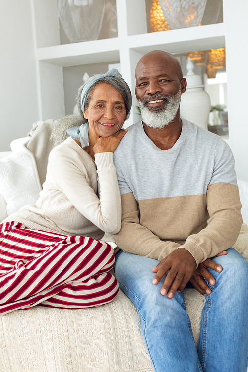 Front view of senior diverse couple sitting in a white room in beach house. Authentic Senior Retired Life Concept