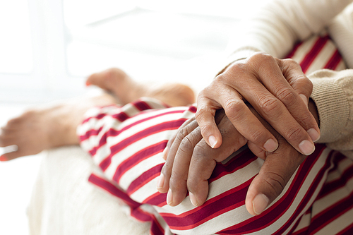 Close-up of happy senior diverse couple hands on top of each other. Authentic Senior Retired Life Concept