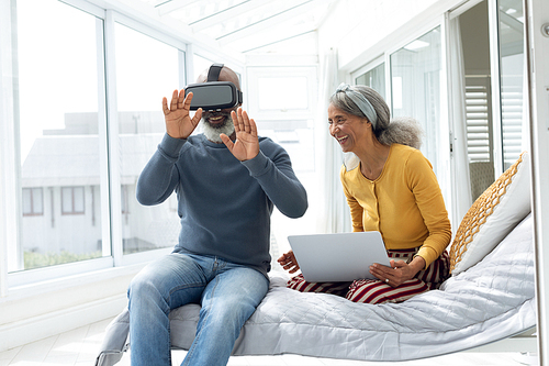 Front view of African American Couple sitting on bed while using digital devices. Authentic Senior Retired Life Concept