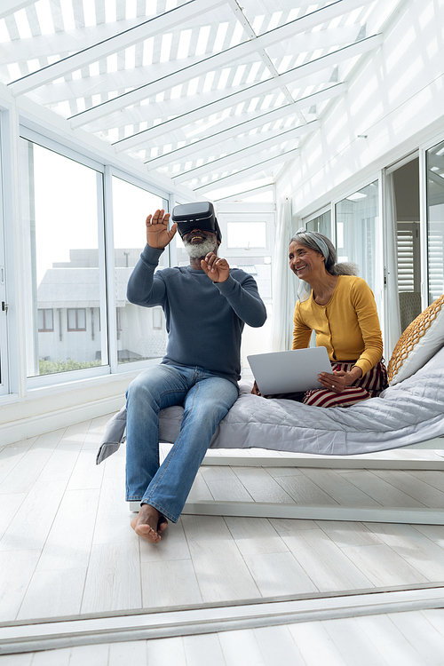 Front view of African American Couple sitting on bed while using digital devices. Authentic Senior Retired Life Concept