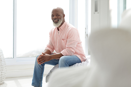 Side view of African American Man sitting on the bed in the bedroom. Authentic Senior Retired Life Concept