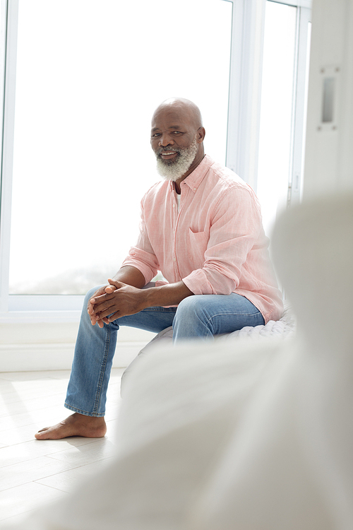 Side view of African American Man sitting on the bed in the bedroom. Authentic Senior Retired Life Concept