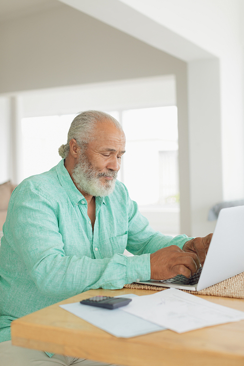 Side view of African-American man using laptop on table indoor. Authentic Senior Retired Life Concept