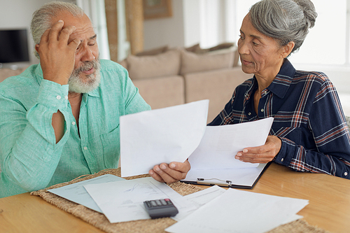 Front view of concerned African-American couple doing finances on the table indoor. Authentic Senior Retired Life Concept