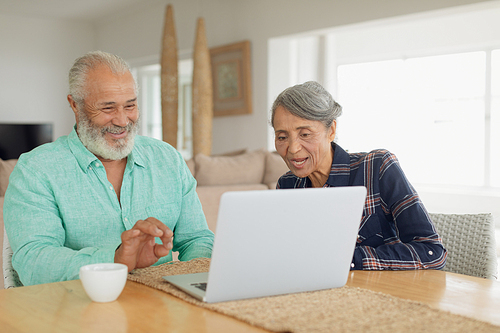 Side view of African-American couple using laptop on table inside a room indoor. Authentic Senior Retired Life Concept