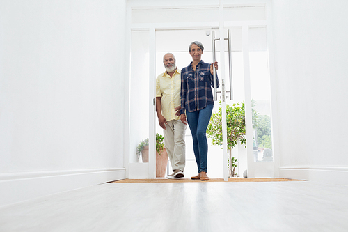 Front view of senior mixed race couple standing in the hall at home. Authentic Senior Retired Life Concept