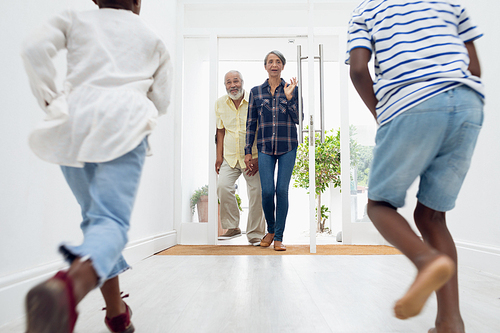 Rear view of African american children running to their grandparents in the hall at home. Authentic Senior Retired Life Concept