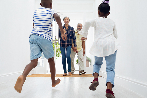 Rear view of African american children running to their grandparents in the hall at home. Authentic Senior Retired Life Concept