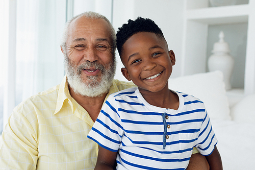 Portrait close up of African-American boy and mixed race man smiling inside a room. Authentic Senior Retired Life Concept